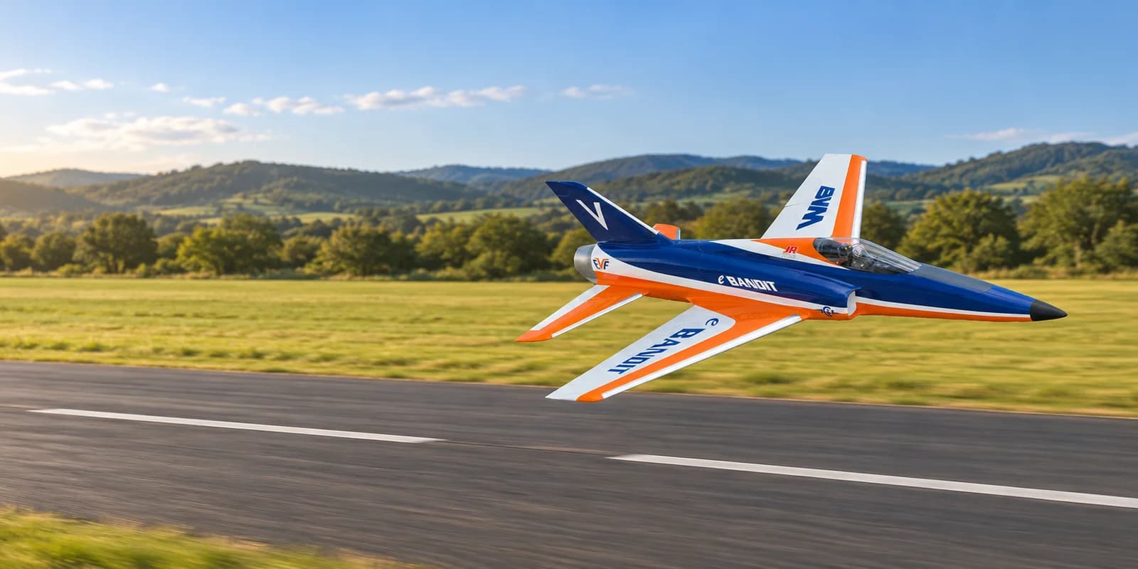 Blue, orange and white RC sport jet making a low runway pass with its landing gear retracted